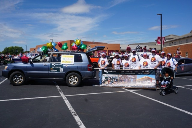 The Kumbha-Yah vehicle covered in balloons, the team lined up behind their banner in the staging lot