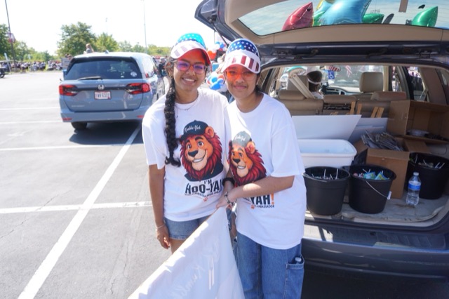Two team members in Hoo-Yah! lion shirts and stars-and-stripes visors, smiling at the camera